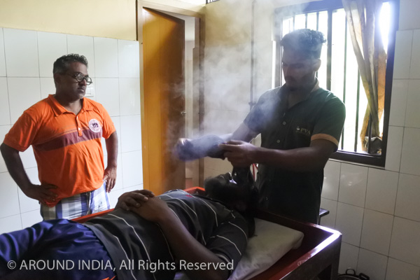 インドのアーユルヴェーダ病院男性セラピストに男性生徒がトリートメントを習っているところ